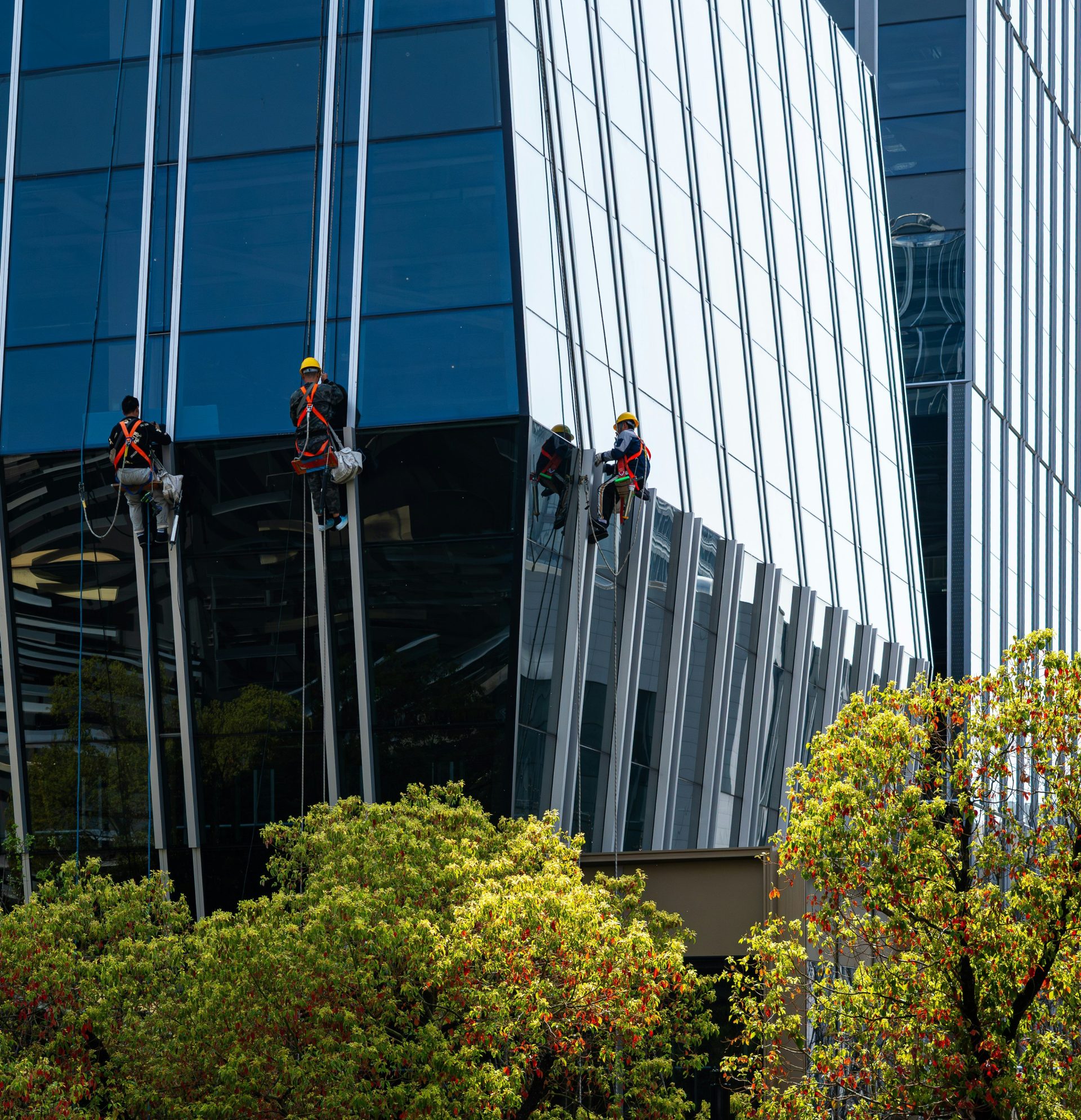 Arbeiter reinigen die Fenster eines modernen Glasgebäudes.