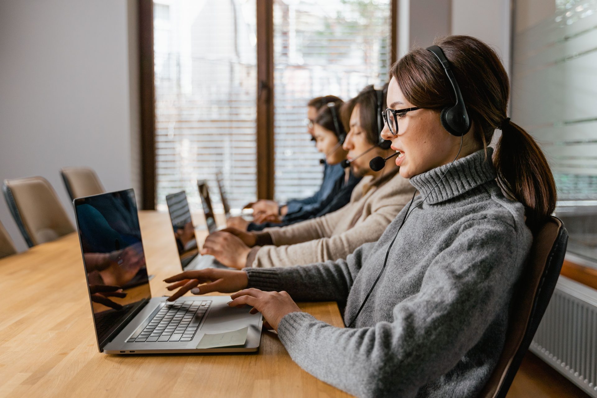 Professionelles Kundenservice-Team, das in einer modernen Büroumgebung mit Headsets und Laptops arbeitet.